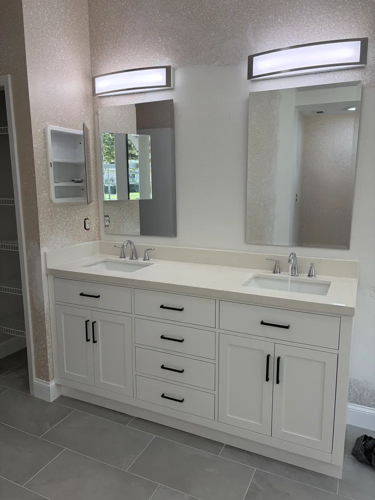 Bathroom with a white shaker double vanity, quartz top, chrome faucets and large-format grey floor tile