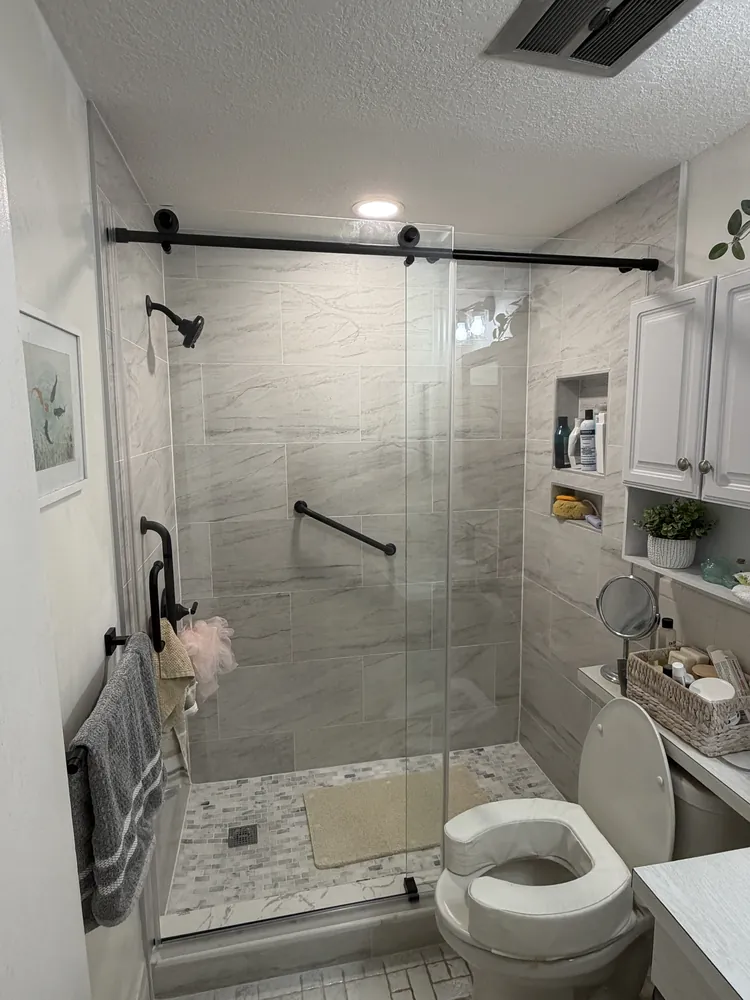 Finished bathroom with a sliding glass shower door, mosaic shower floor and wall-mounted grab bars