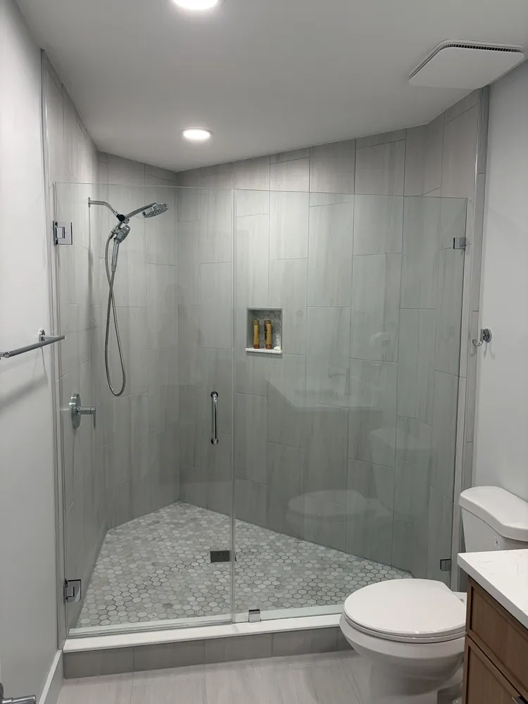 Walk-in shower with frameless glass, a tiled bench and a pebble mosaic floor