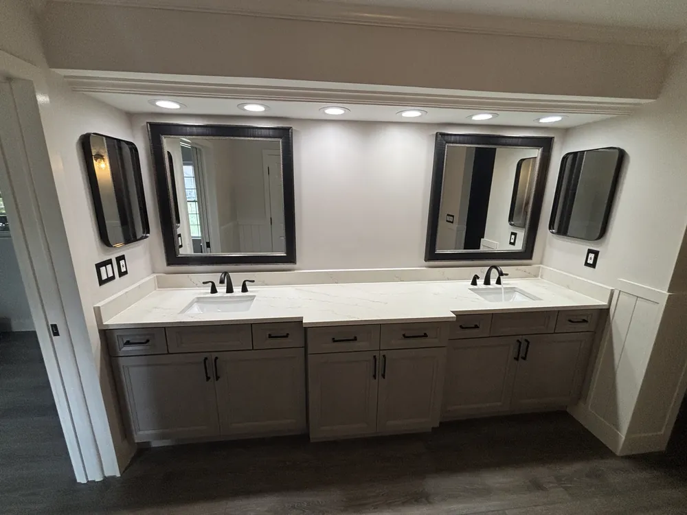 Master bathroom with a long grey double vanity, black-framed mirrors and wood-look plank floor