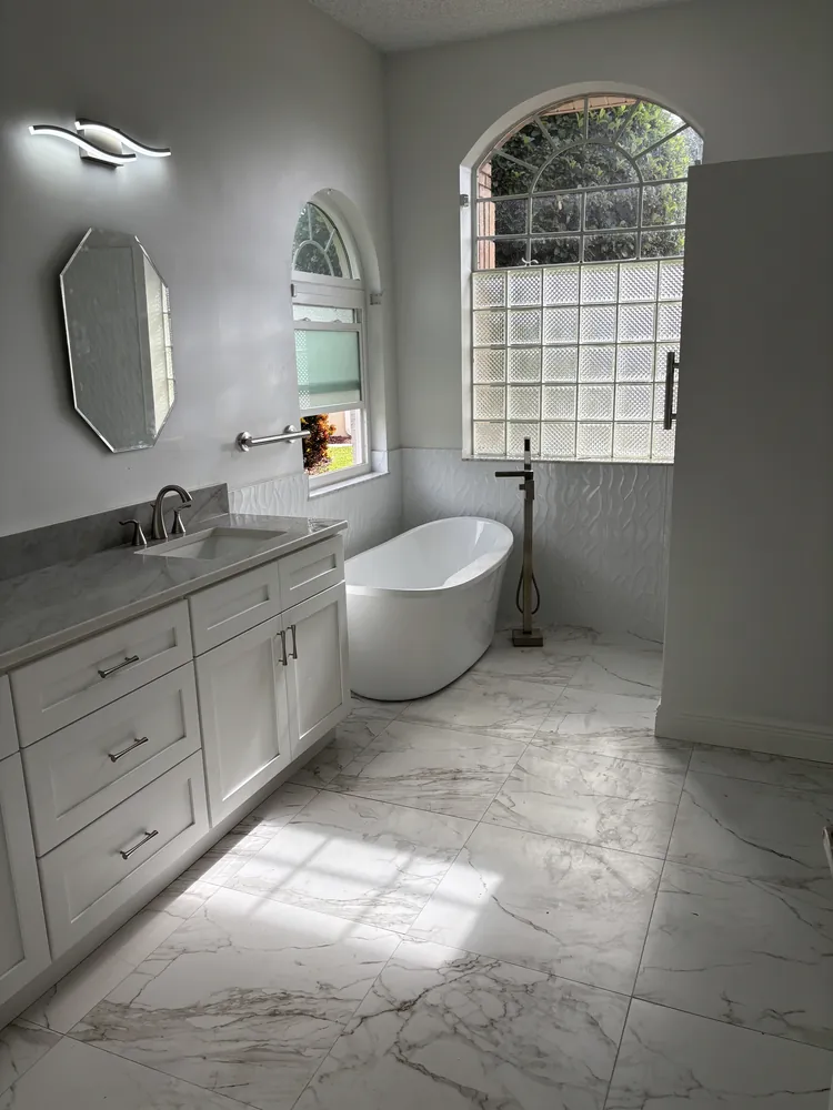 Master bath with a freestanding tub, white shaker vanity and marble-look porcelain floor