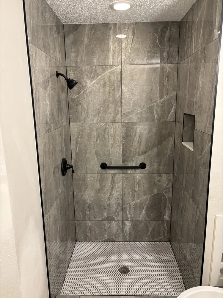 Walk-in shower with dark grey stone-look tile, a niche and matte black fixtures