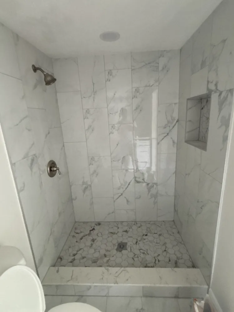 Walk-in shower with marble-look tile, a bench seat and a mosaic floor