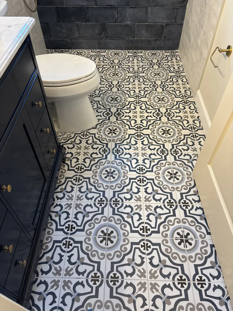 Patterned blue-and-cream floor tile beside a navy vanity cabinet