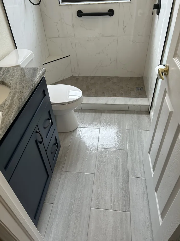 Bathroom with marble-look floor tile, a navy vanity and black fixtures