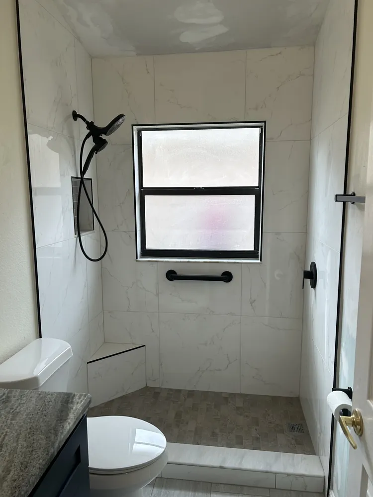 Tiled shower with a window, matte black fixtures and a built-in bench