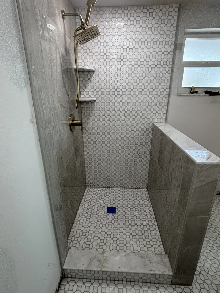 Shower with patterned feature wall, brass fixtures and a marble hexagon floor