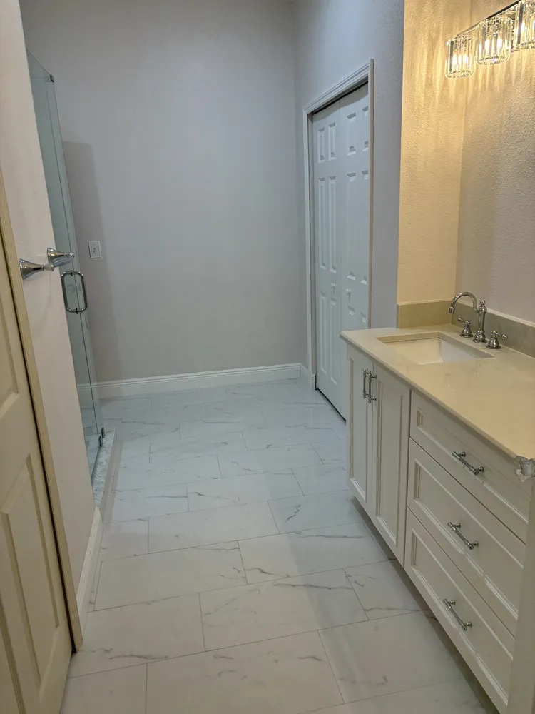 Master bathroom with a white vanity, chrome faucets and large-format marble-look floor