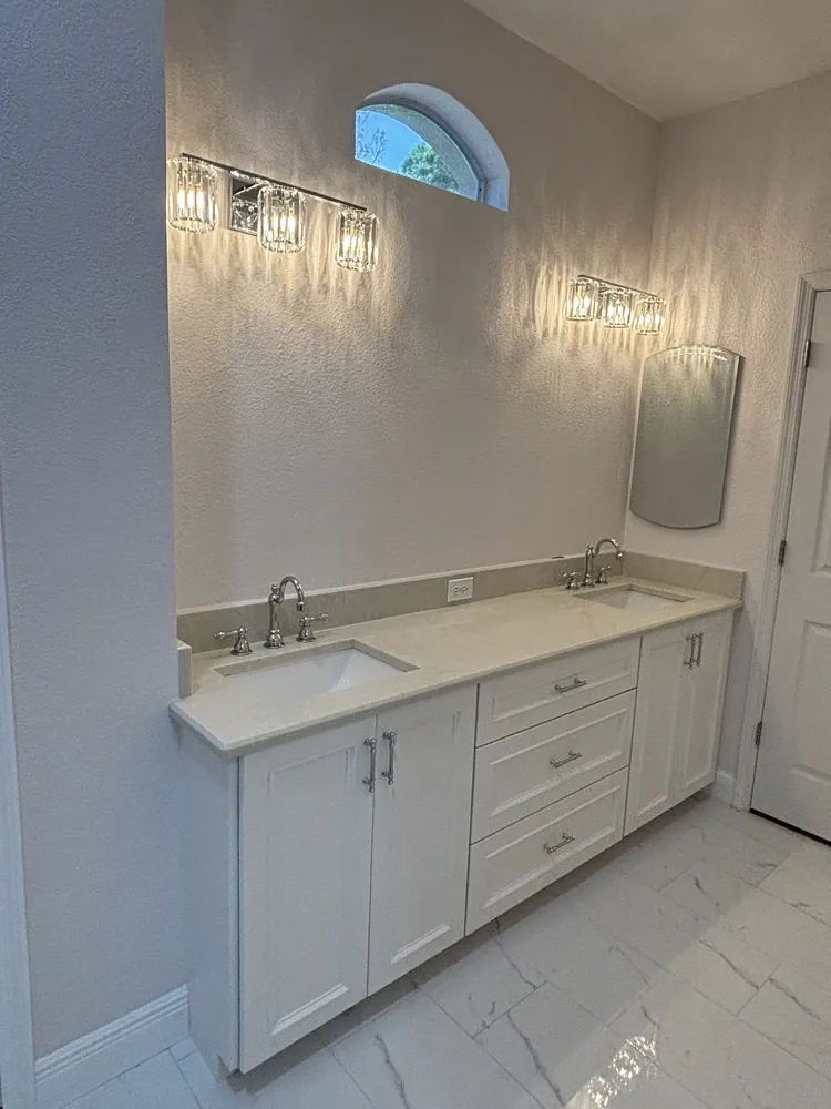 Double vanity with sconce lighting below an arched window in a remodeled bathroom