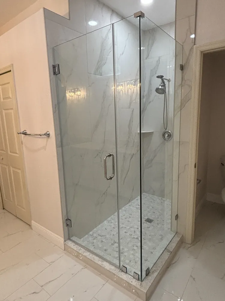 Frameless glass shower with marble-look tile and a hexagon mosaic floor