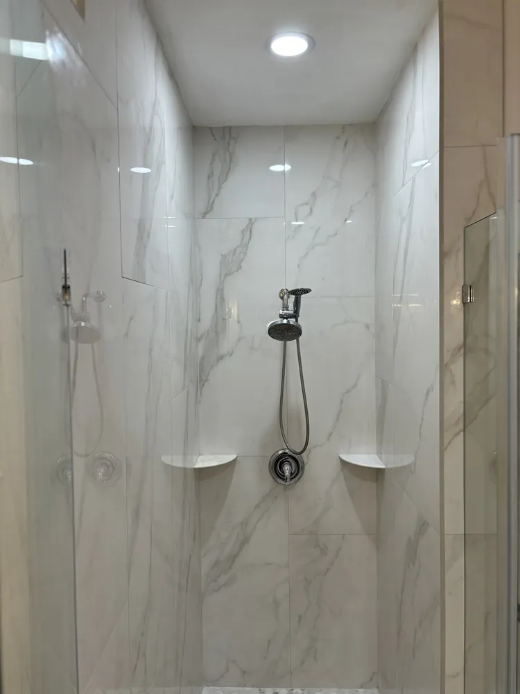 Marble-look shower with corner shelves and a hand shower