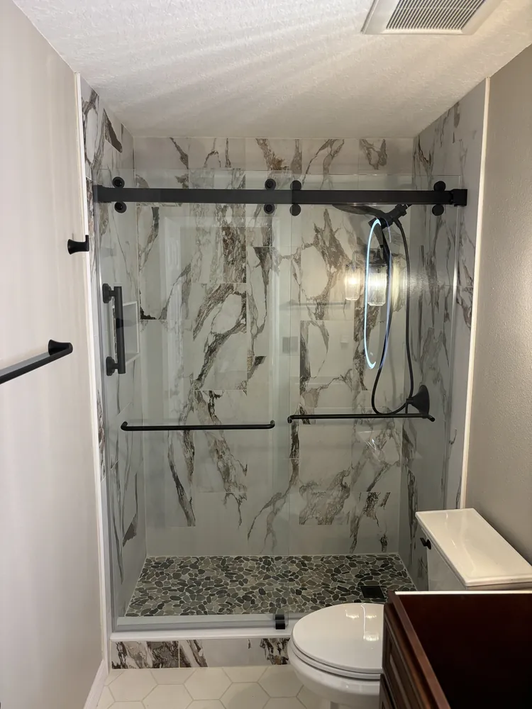 Shower with bold marble-look tile and a black-framed sliding glass door