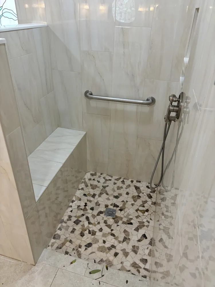 Accessible walk-in shower with a built-in bench, grab bars and pebble floor