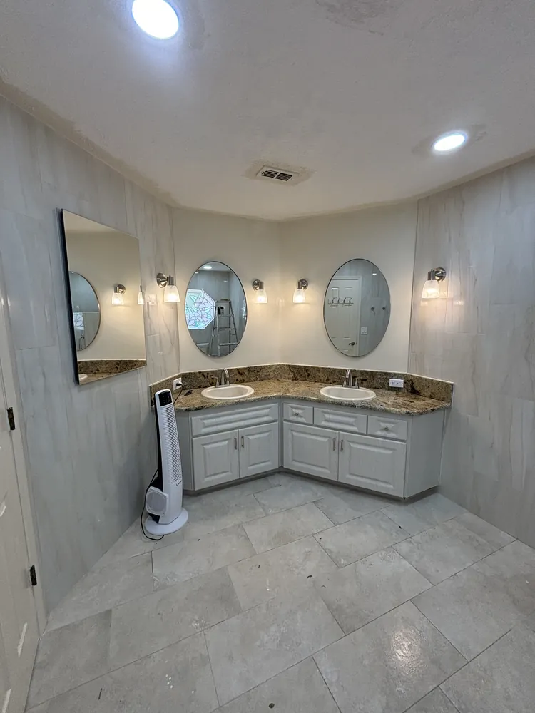 Corner double vanity with granite top, round mirrors and large-format floor tile