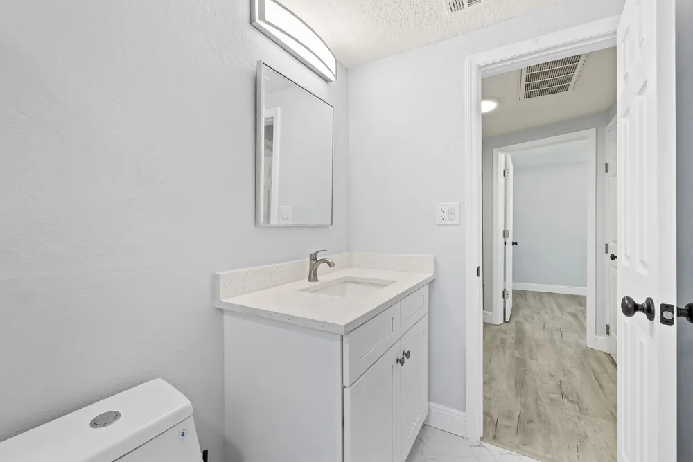 Guest bathroom with a white vanity, quartz top and wood-look plank floor