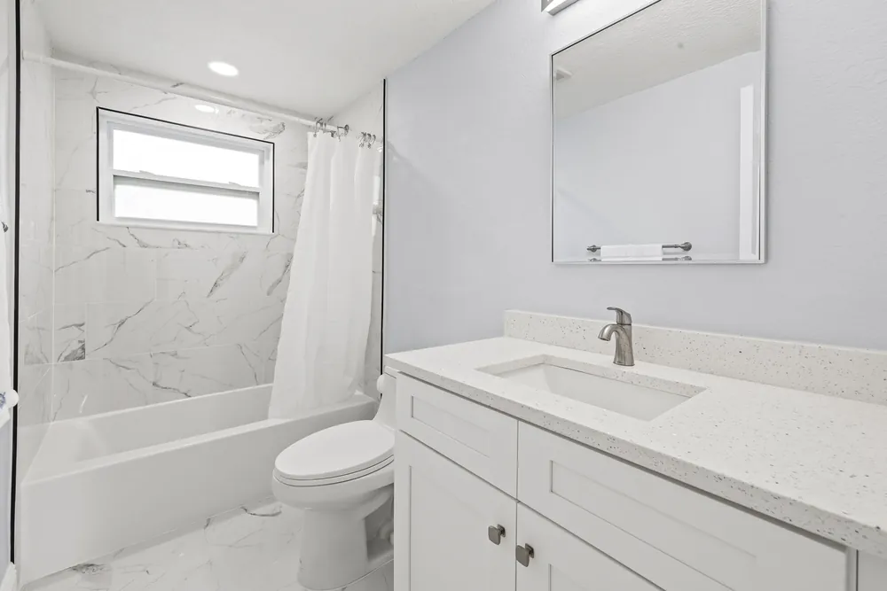 Tub and shower with marble-look wall tile and a new white vanity