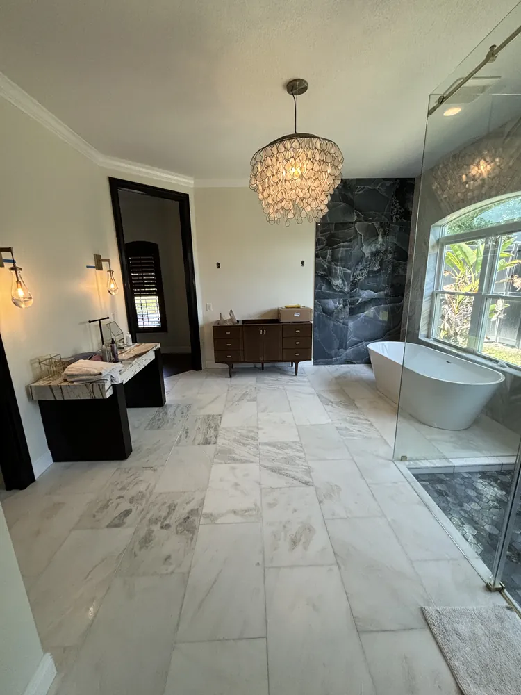 Luxury master bath with a freestanding tub, crystal chandelier and dark stone shower wall