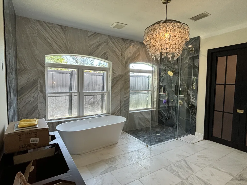 Luxury master bathroom with a chevron tile feature wall, freestanding tub and frameless glass shower
