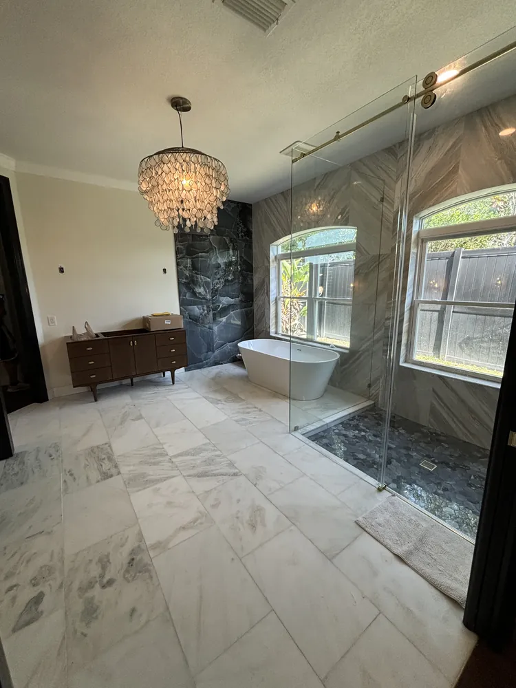 Master bath with a frameless glass shower, chandelier and marble-look floor