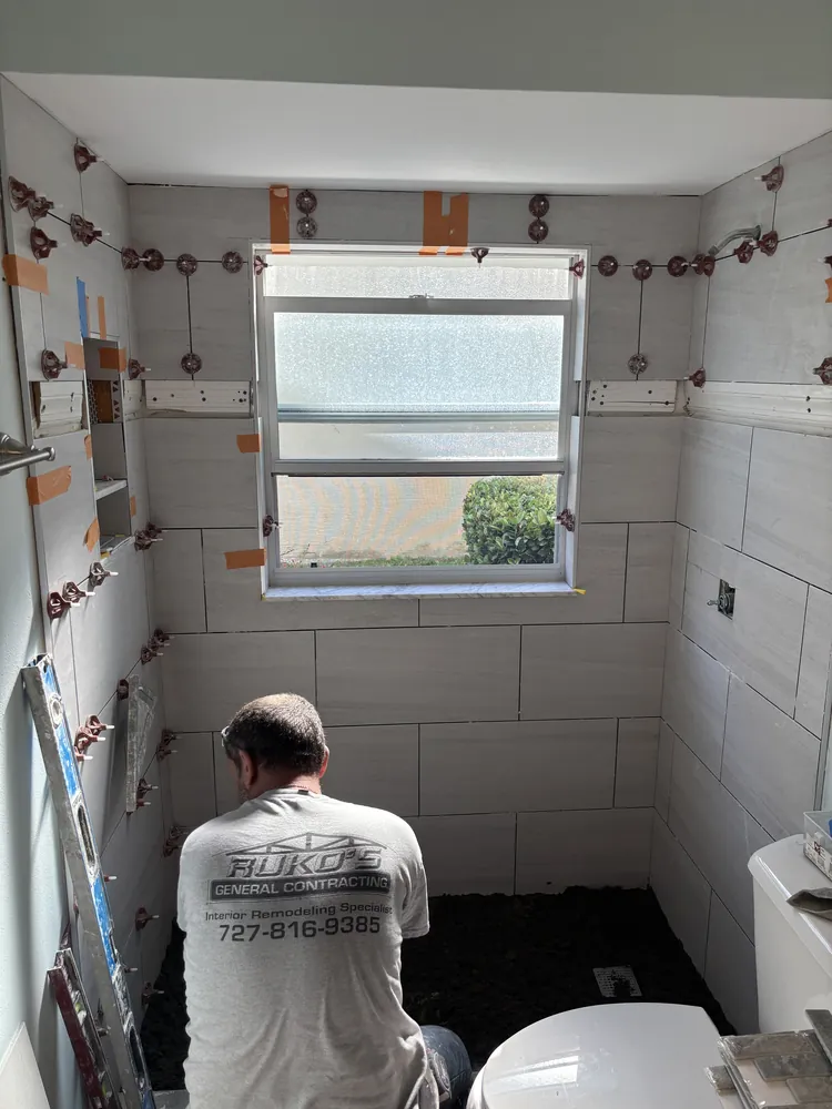 Ruko's tile installer setting shower wall tile with leveling clips