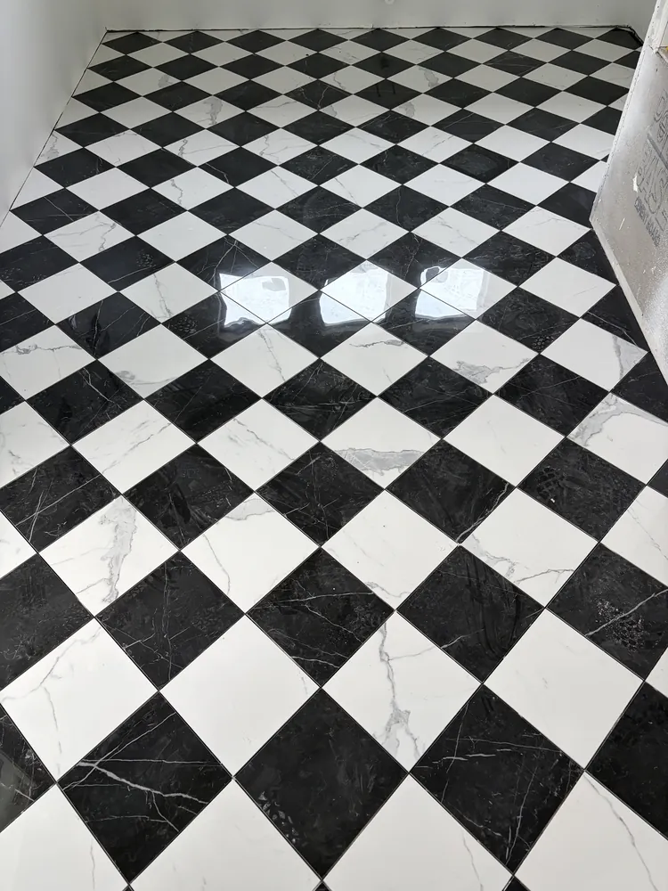 Black-and-white checkerboard marble-look floor tile laid on the diagonal