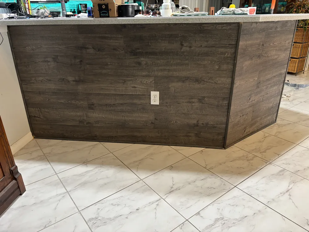 Home bar wrapped in reclaimed-look wood planks over a marble-look tile floor