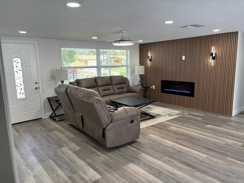 Living room with a wood slat accent wall, electric fireplace and wood-look plank floor