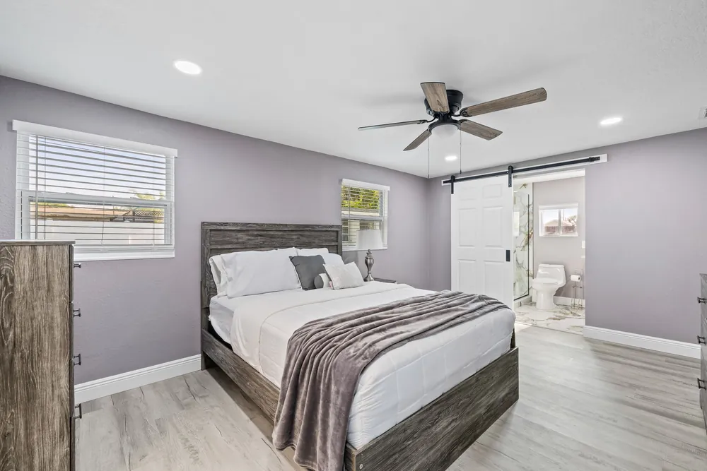 Remodeled bedroom with plank flooring and a barn door to the bathroom