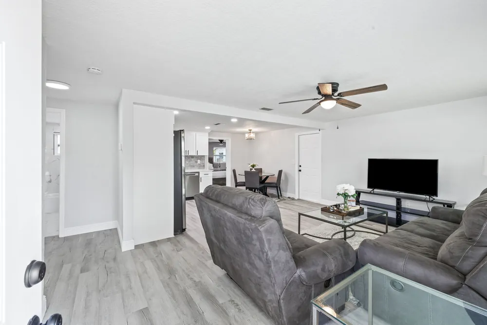 Living room opening to a remodeled kitchen with matching plank flooring