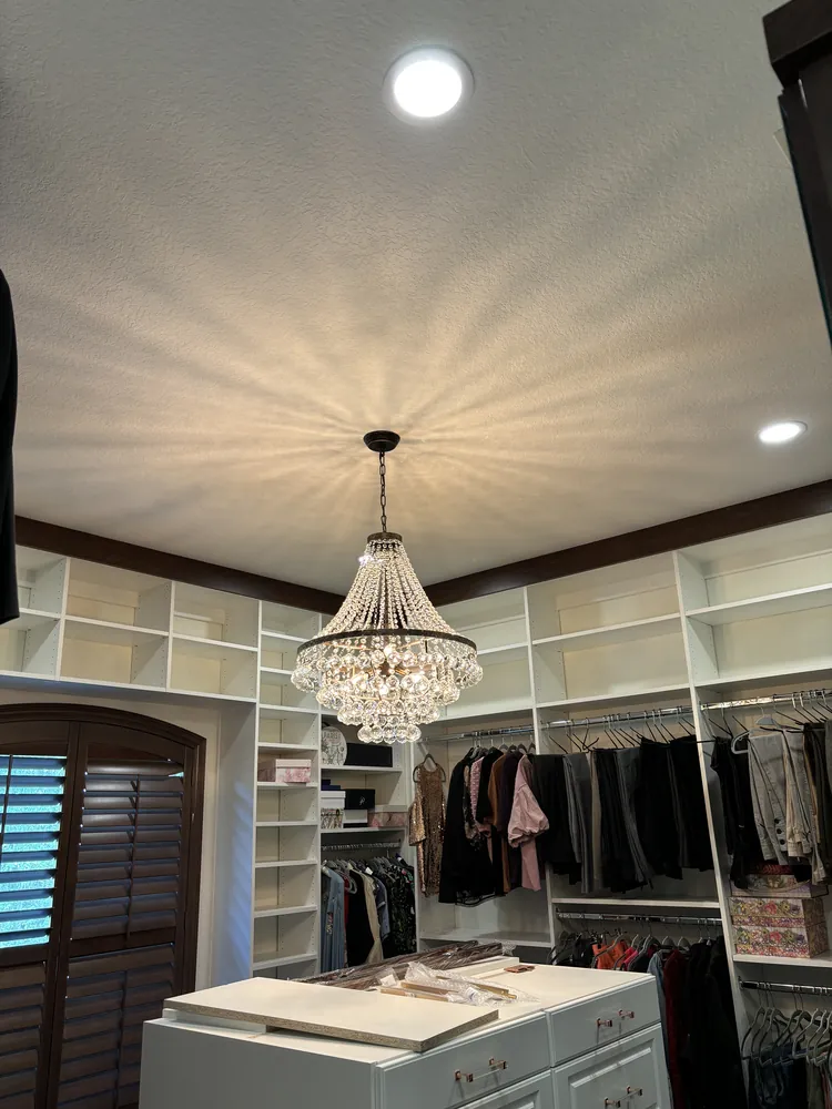Custom walk-in closet with built-in shelving, a center island and a chandelier