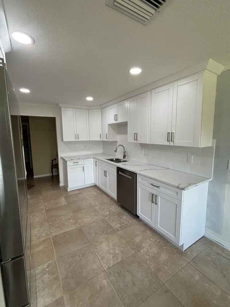 Kitchen with white shaker cabinets, marble-look quartz counters and large-format tile floor