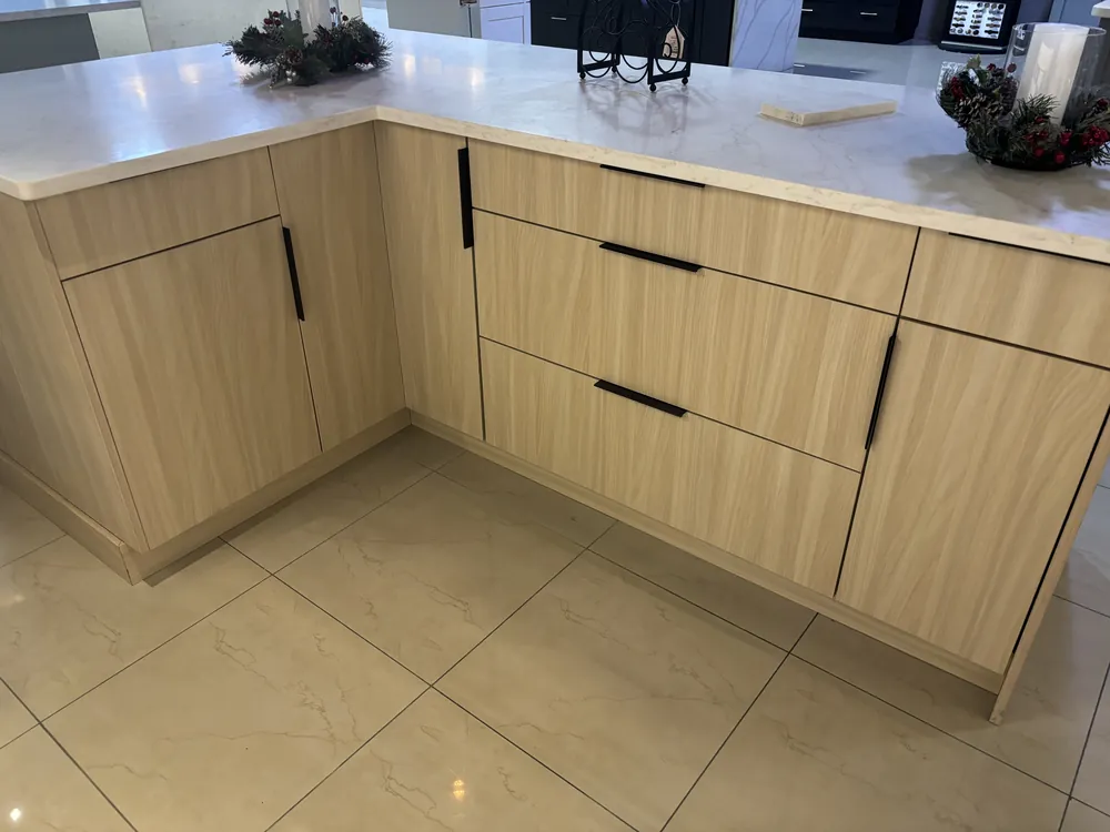Kitchen with light wood flat-panel cabinets, white quartz counters and black hardware