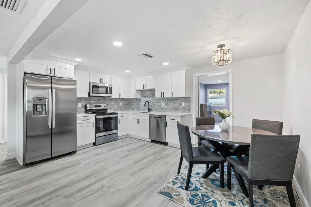 Open-plan kitchen and dining area with white cabinets and wood-look plank floor